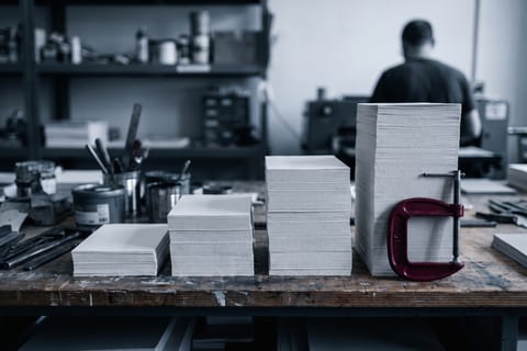 Four paper stacks of increasing height on a workbench